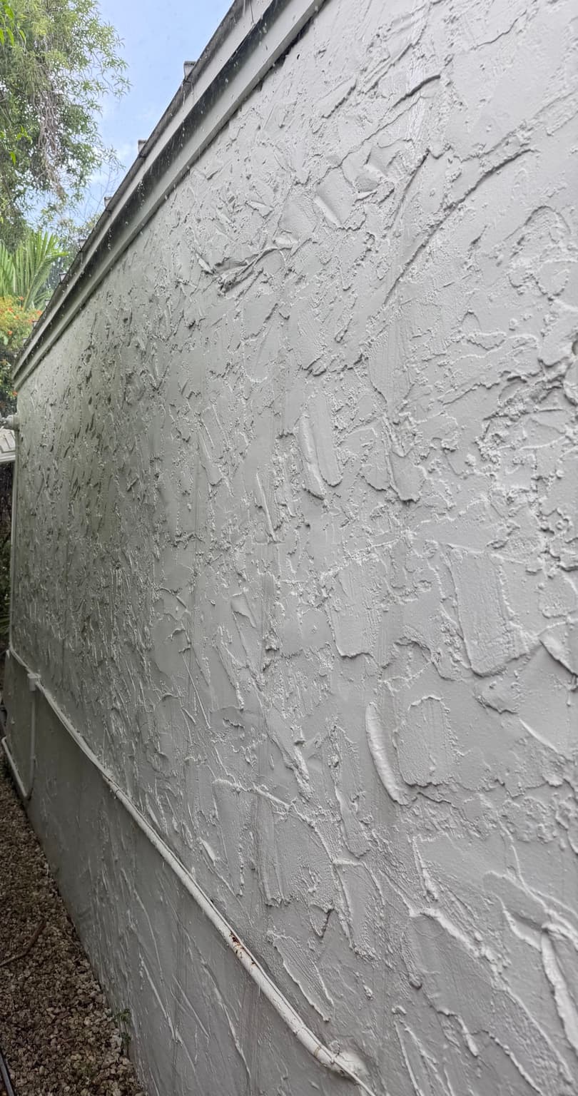 After house soft washing showing cleaned white stucco wall