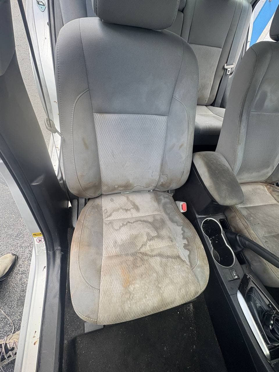 Before mobile car detailing showing a heavily stained gray cloth front seat