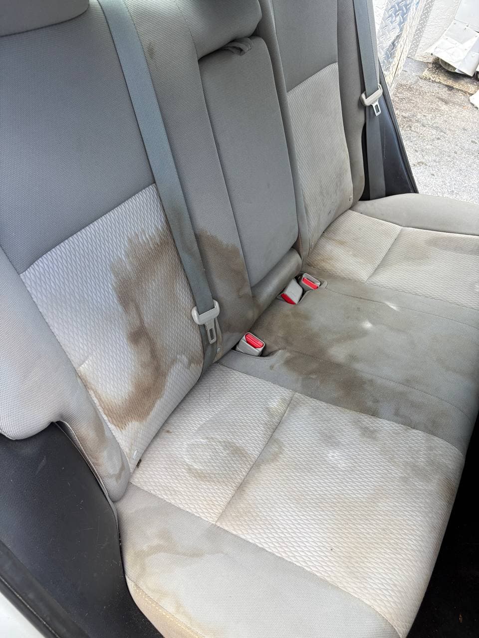 Before mobile detailing showing a stained rear cloth bench seat